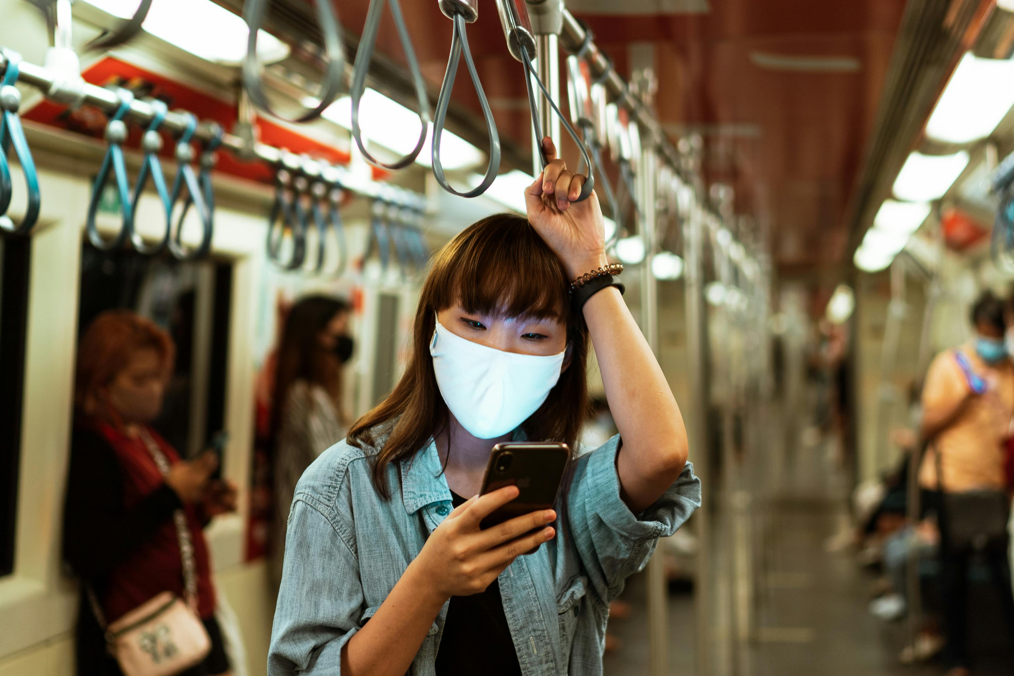 Woman Wearing a Face Mask on the Subway and Using her Smartphone ...